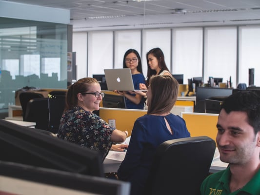 people talking at desk and working on computer